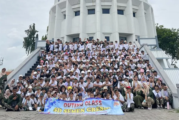 Siswa berfoto dengan latar belakang meriam kapal perang KRI