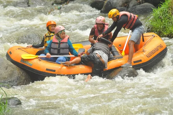 Sesi foto bersama rombongan dengan latar belakang sungai dan basecamp rafting